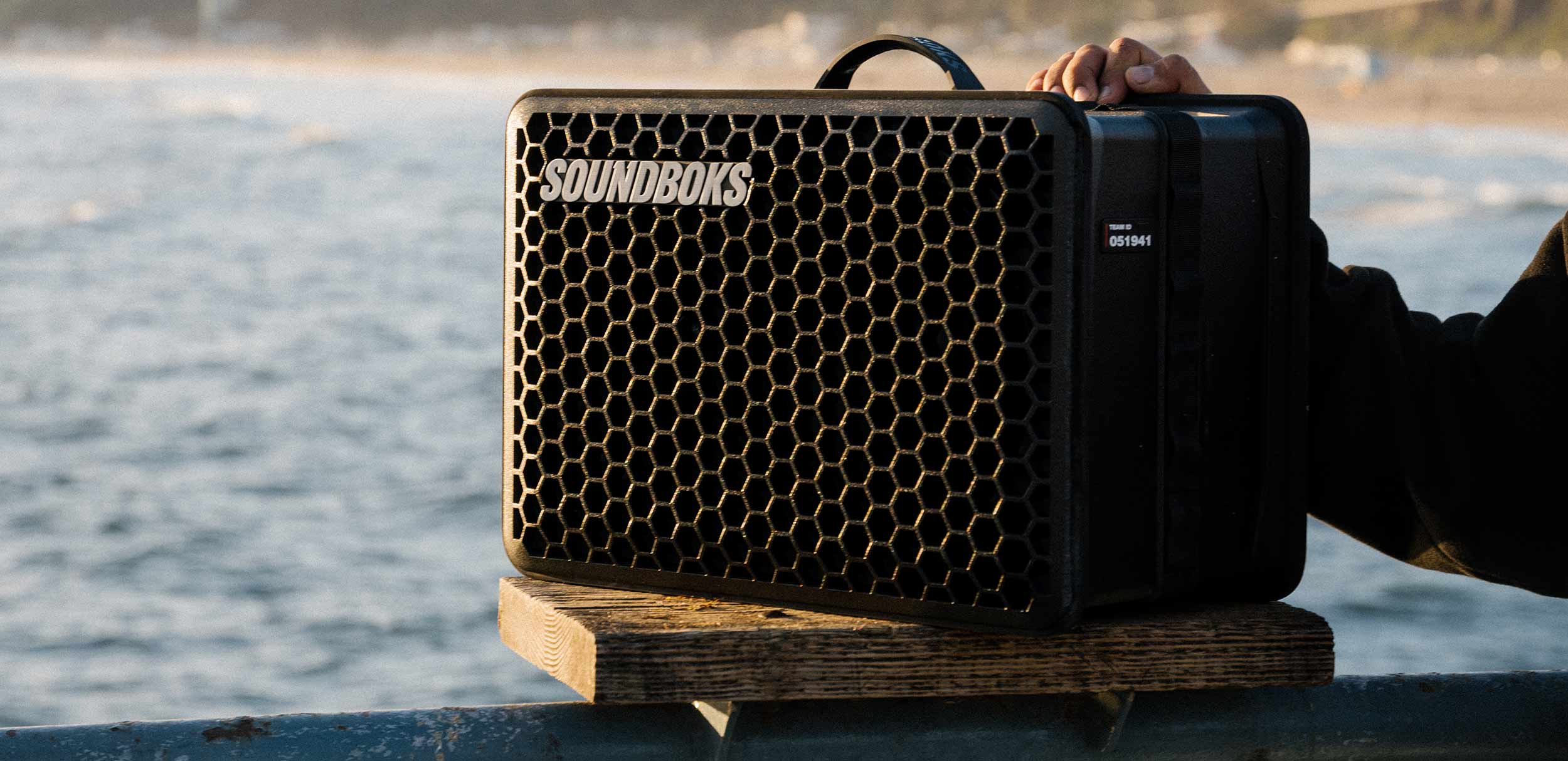 A SOUNDBOKS Go standing on a fence in the sunset overlooking the sea